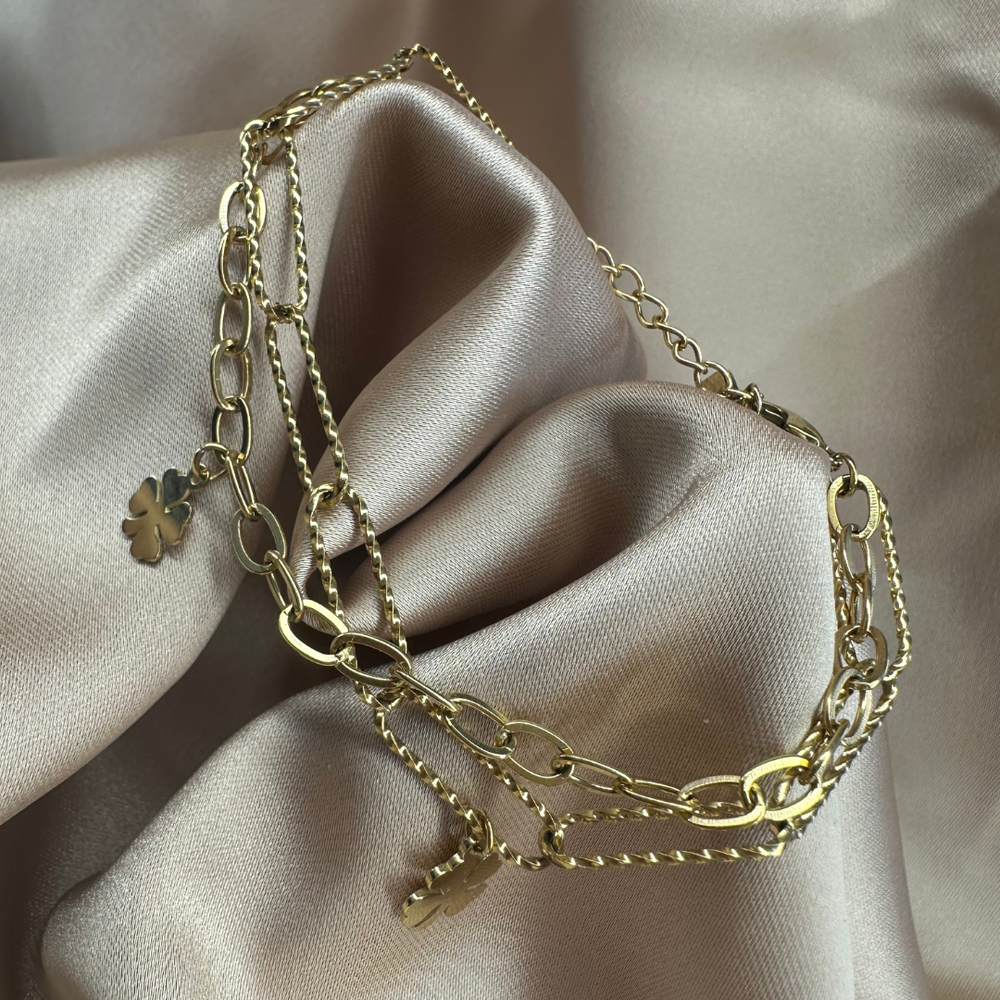 Close-up van de Double Lucky Clover armband, met twee armbandjes in één: een grove schakel en een subtiele schakel, beide met twee klavertje vier bedeltjes, gemaakt van stainless steel, hypoallergeen, waterproof en verkleurt niet.