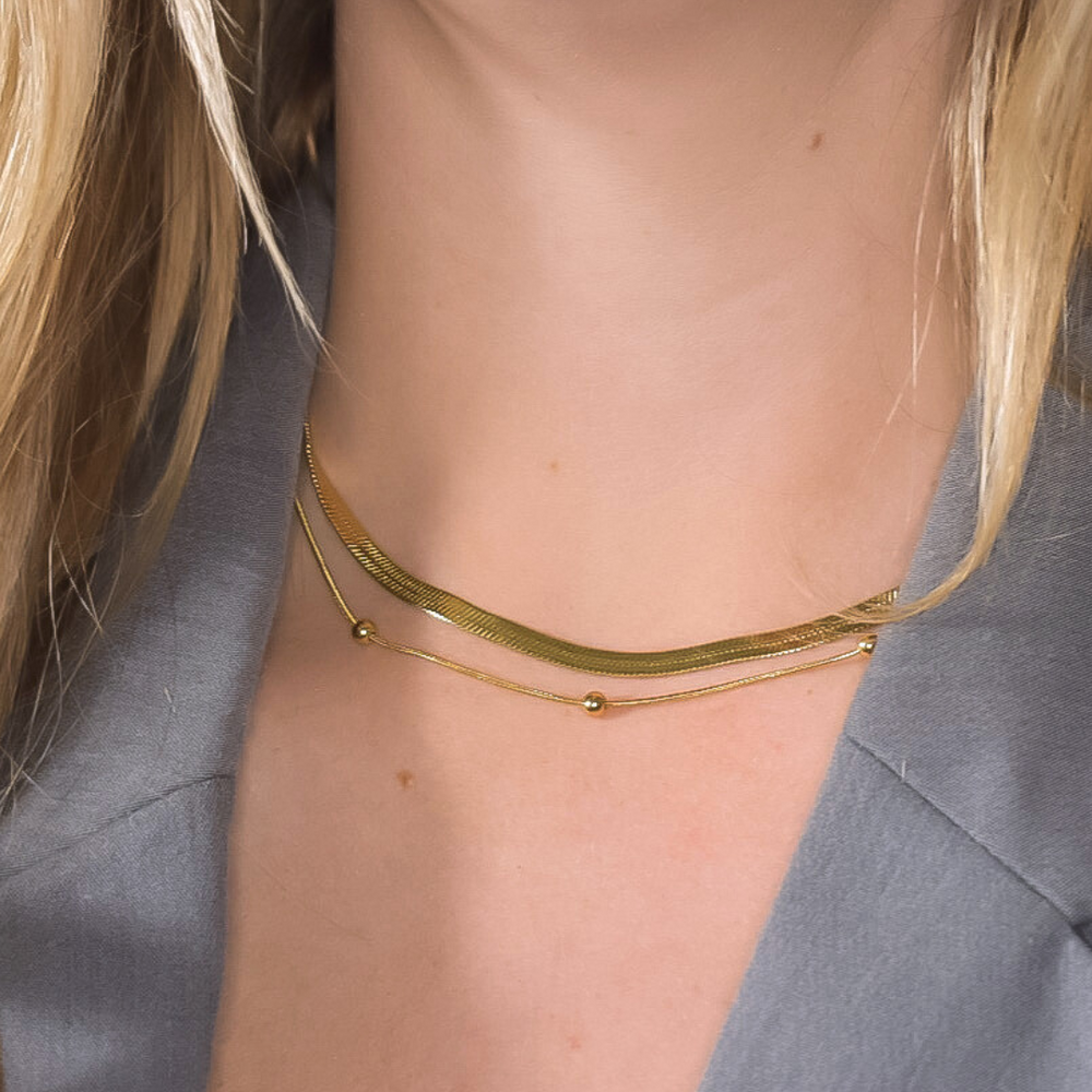 Close-up van de Faye ketting, bestaande uit twee lagen: een brede gouden ketting en een dunne gouden ketting met bolletjes, gemaakt van stainless steel, hypoallergeen, waterproof en verkleurt niet.