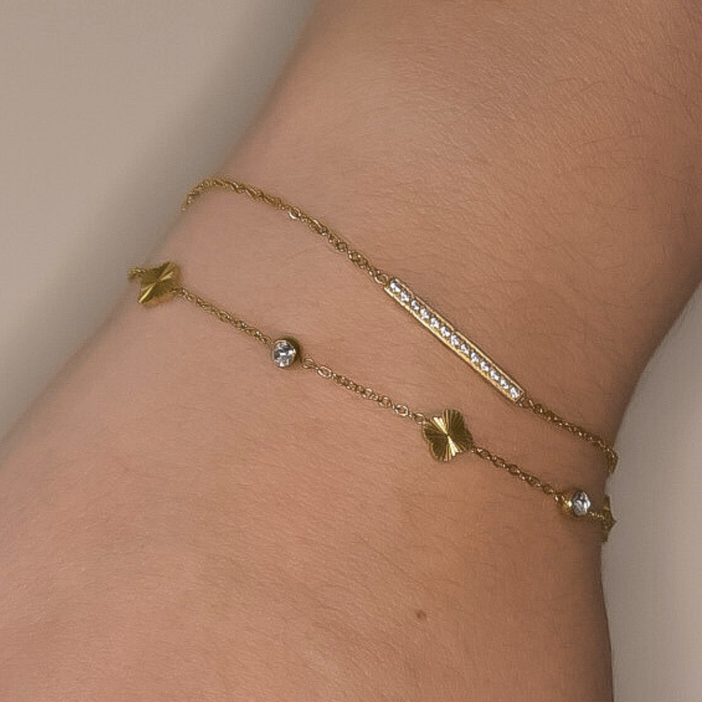 Close-up van de Golden Clover armband, met een klavertje vier bedeltje en kleine bedeltjes met zilveren steentjes, gemaakt van stainless steel in goud, hypoallergeen, waterproof en verkleurt niet.