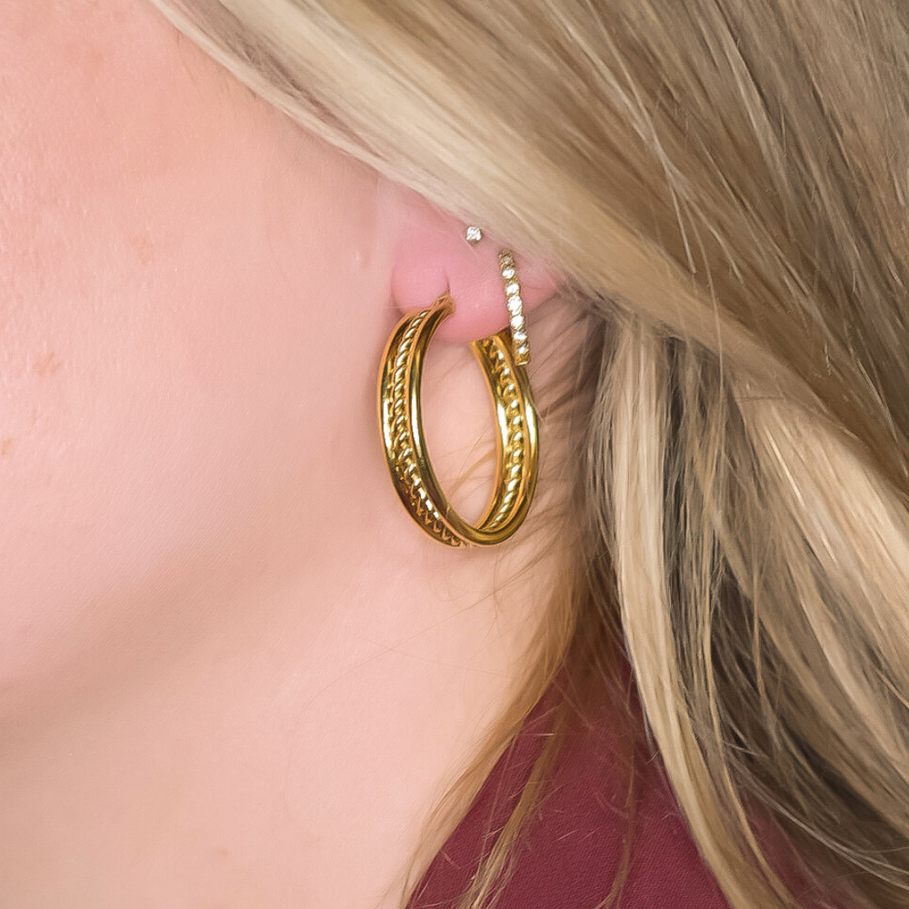 Close-up van de Ruby Oorbellen met drie banen: buitenste banen in subtiel goud en een middelste baan met een gouden twirl, gemaakt van stainless steel, hypoallergeen, waterproof en verkleuren niet.