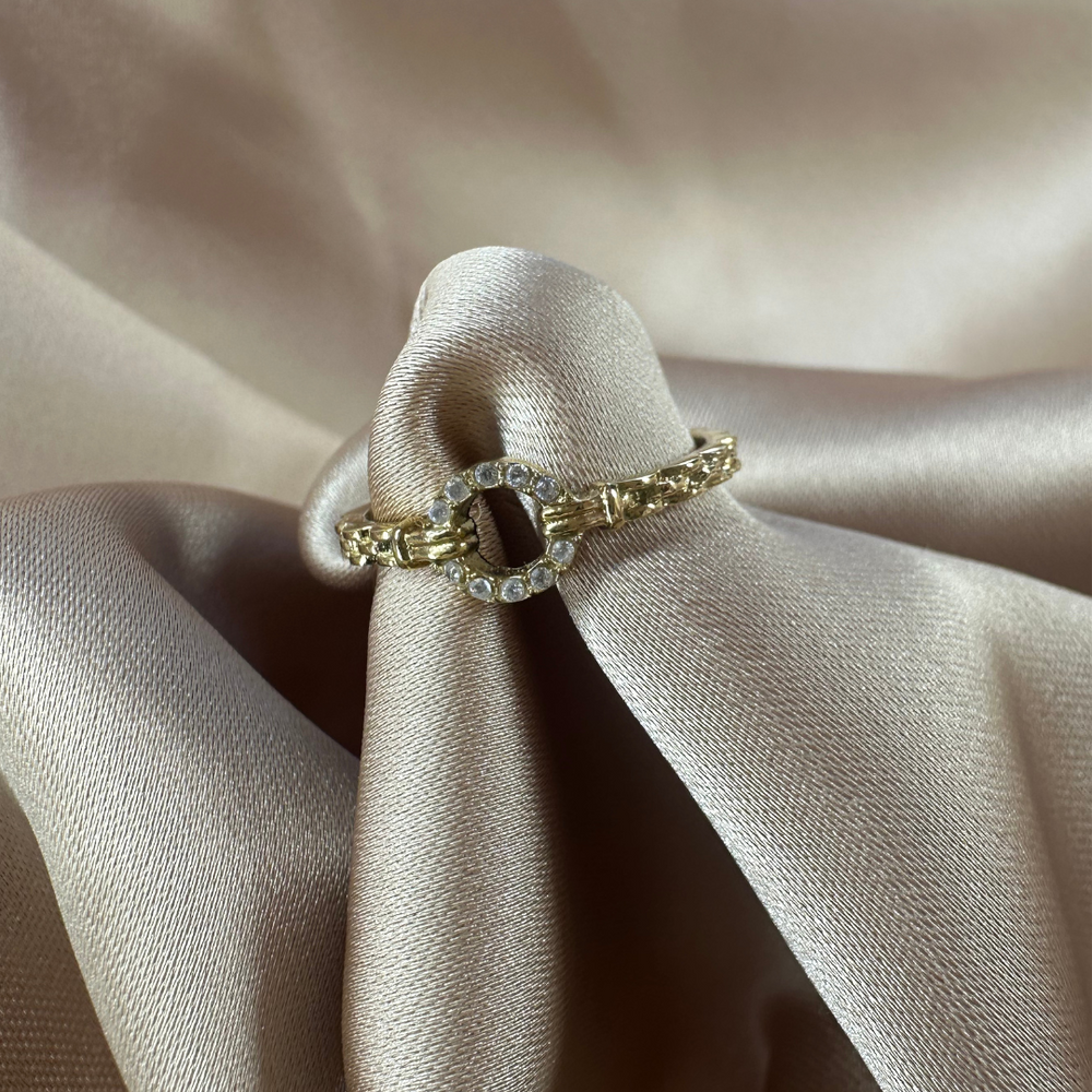 Een goudgevlochten ring met een ovaal detail, versierd met zilveren stras steentjes, gemaakt van stainless steel; hypoallergeen, waterproof en kleurvast.