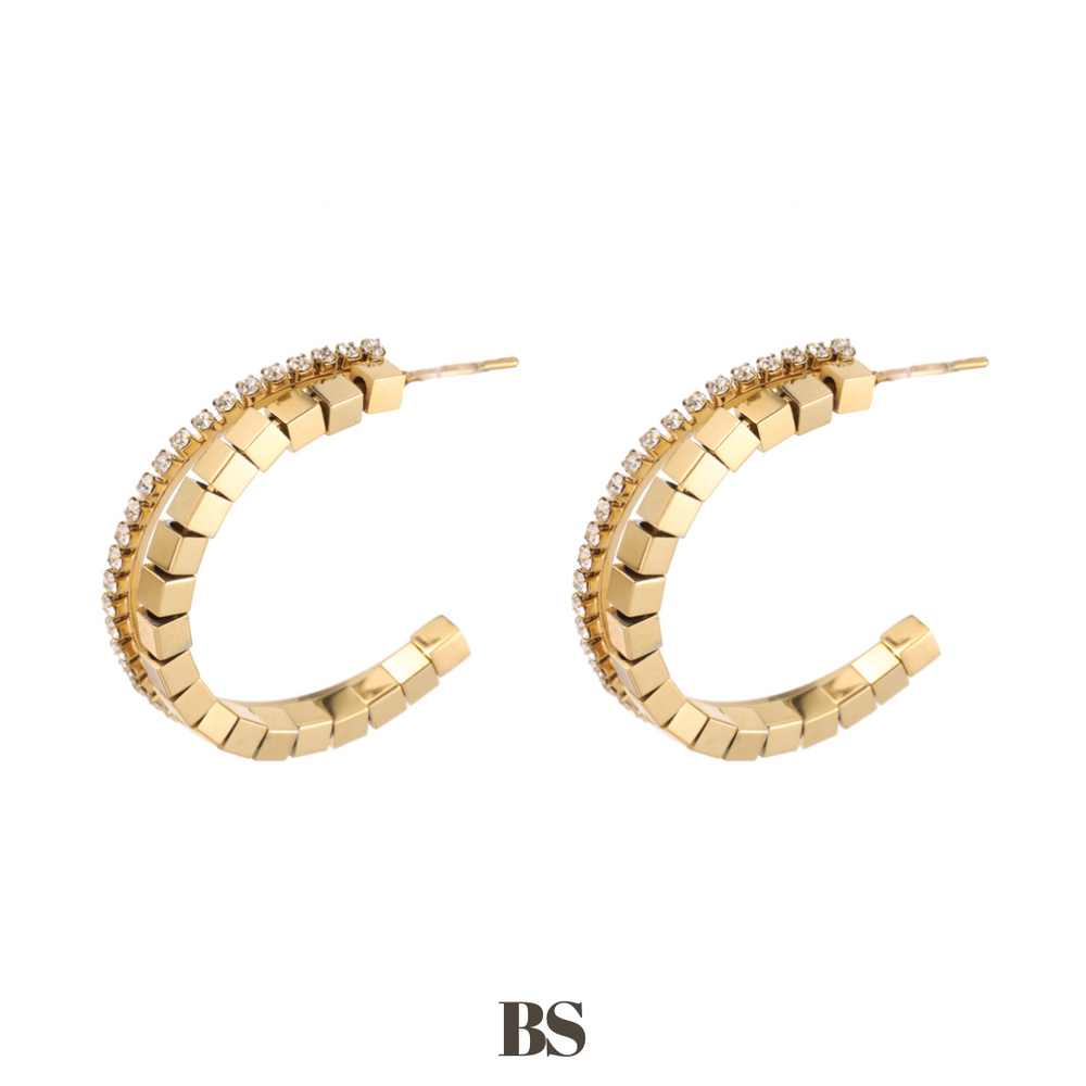 Close-up van de Lily oorbellen, met een gouden ringdesign en een rij van vierkante gouden kraaltjes en zilveren stras steentjes, gemaakt van stainless steel, hypoallergeen, waterproof en verkleuren niet.