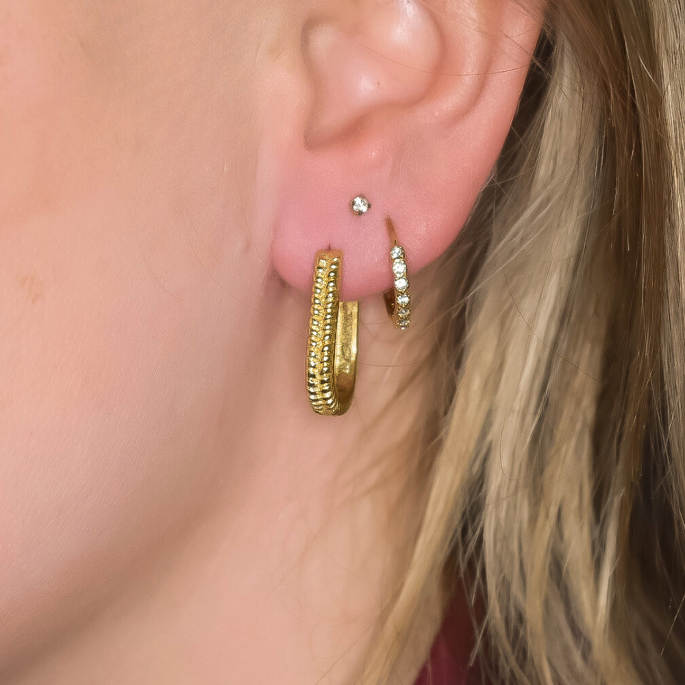 Close-up van de gold Zoë oorbellen in goud, met een subtiele werking in het ontwerp, gemaakt van stainless steel, hypoallergeen, waterproof en verkleuren niet.